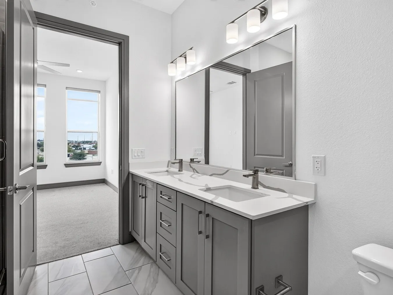 Dual vanity with gray shaker cabinetry, undermount sinks, and light-toned countertops
