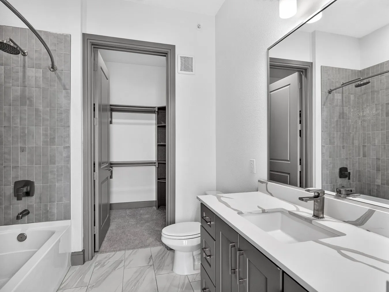 Spacious bathroom featuring a single vanity with storage, a shower/tub combination with subway tile surround, and tile flooring