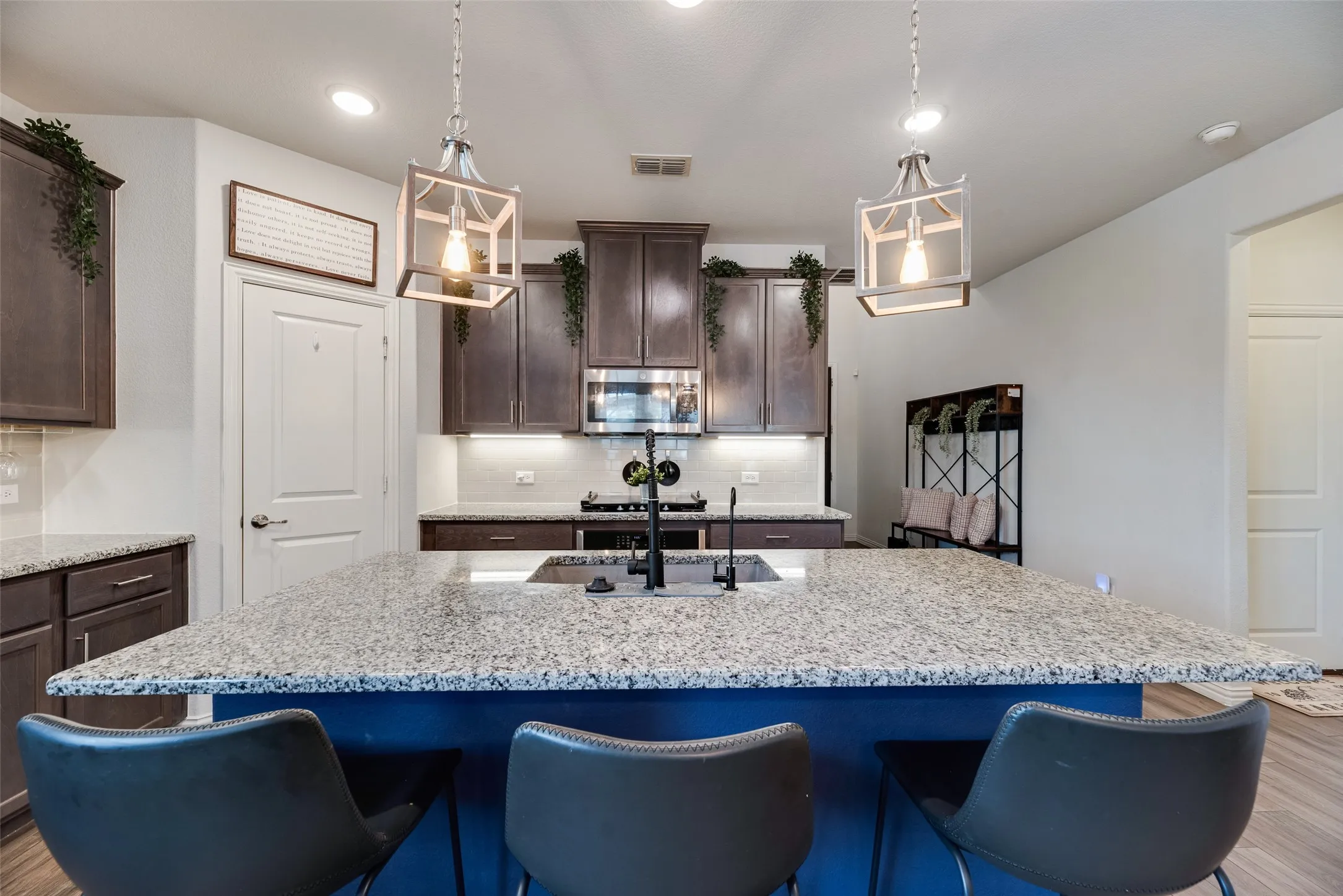 Kitchen features an expansive island with granite countertops, dark wood cabinetry, and stainless steel appliances!