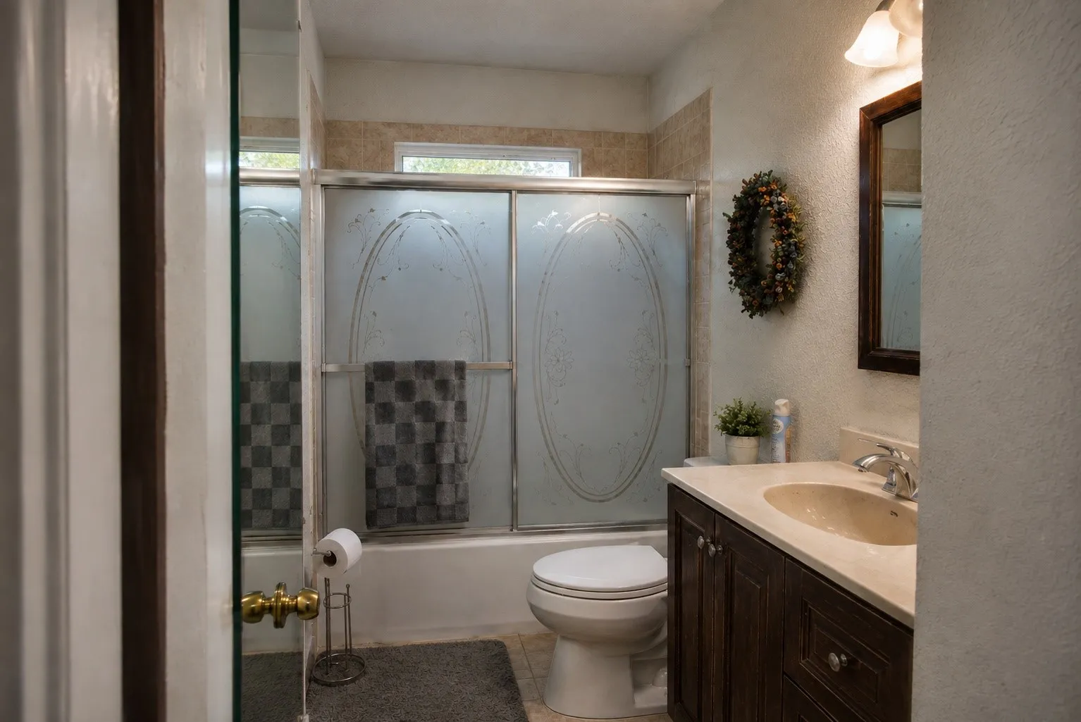 Spa-inspired bathroom featuring a frameless glass-enclosed shower with decorative tile accents, dual vanity with wood-finish cabinetry and white countertop, and brushed nickel fixtures