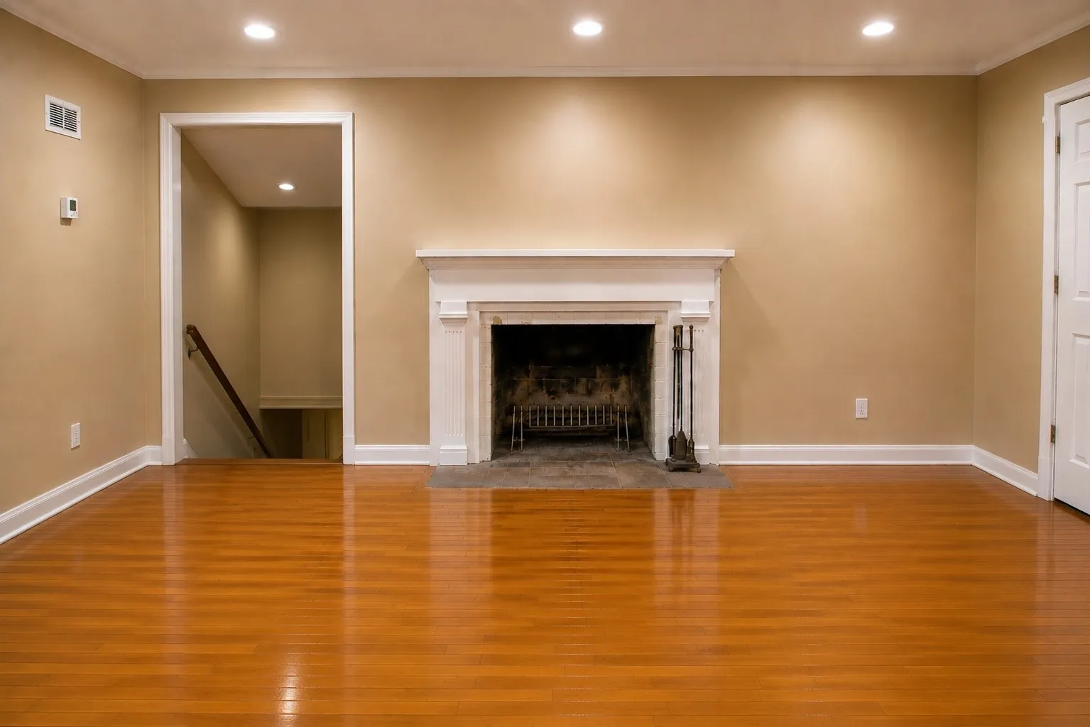 Hardwood flooring, recessed lighting, white trim and baseboards, and a fireplace with a white mantel and hearth