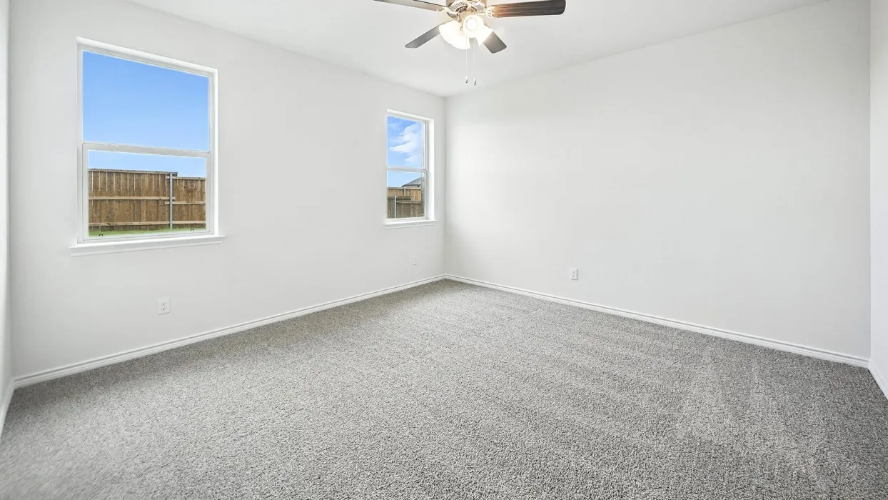 Bright room featuring two windows, neutral gray carpeting, white walls, and a ceiling fan with integrated lighting