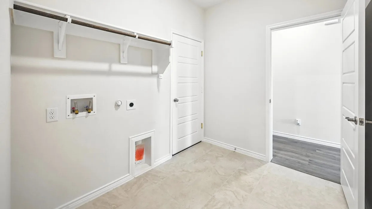 Laundry area with wall-mounted shelving, utility connections, and tile flooring