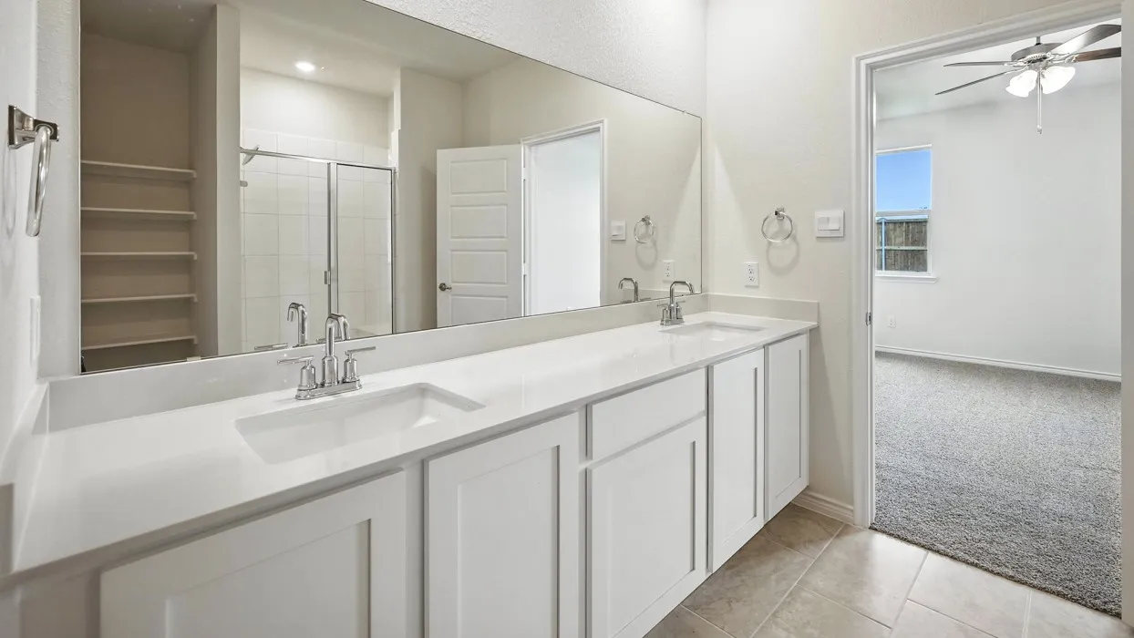 Dual vanity with white cabinetry and integrated sinks, a large wall-mounted mirror, and tile flooring