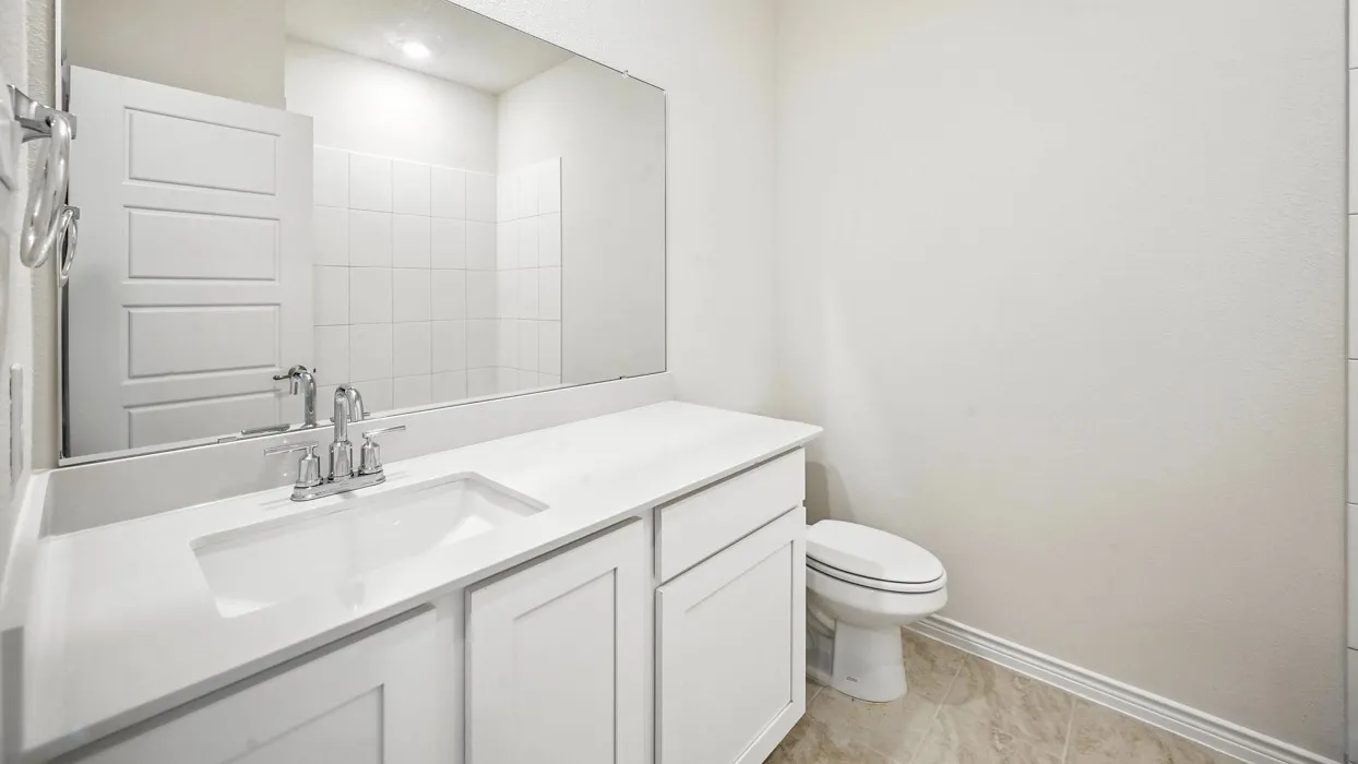 Spa-inspired bathroom featuring a dual-sink vanity with white cabinetry and quartz countertop, chrome faucet fixtures, and an oversized framed mirror