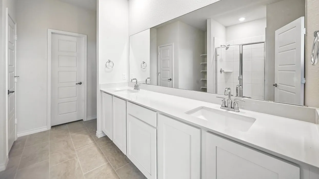 Double vanity with integrated sinks, white cabinetry, chrome fixtures, and a large wall-mounted mirror
