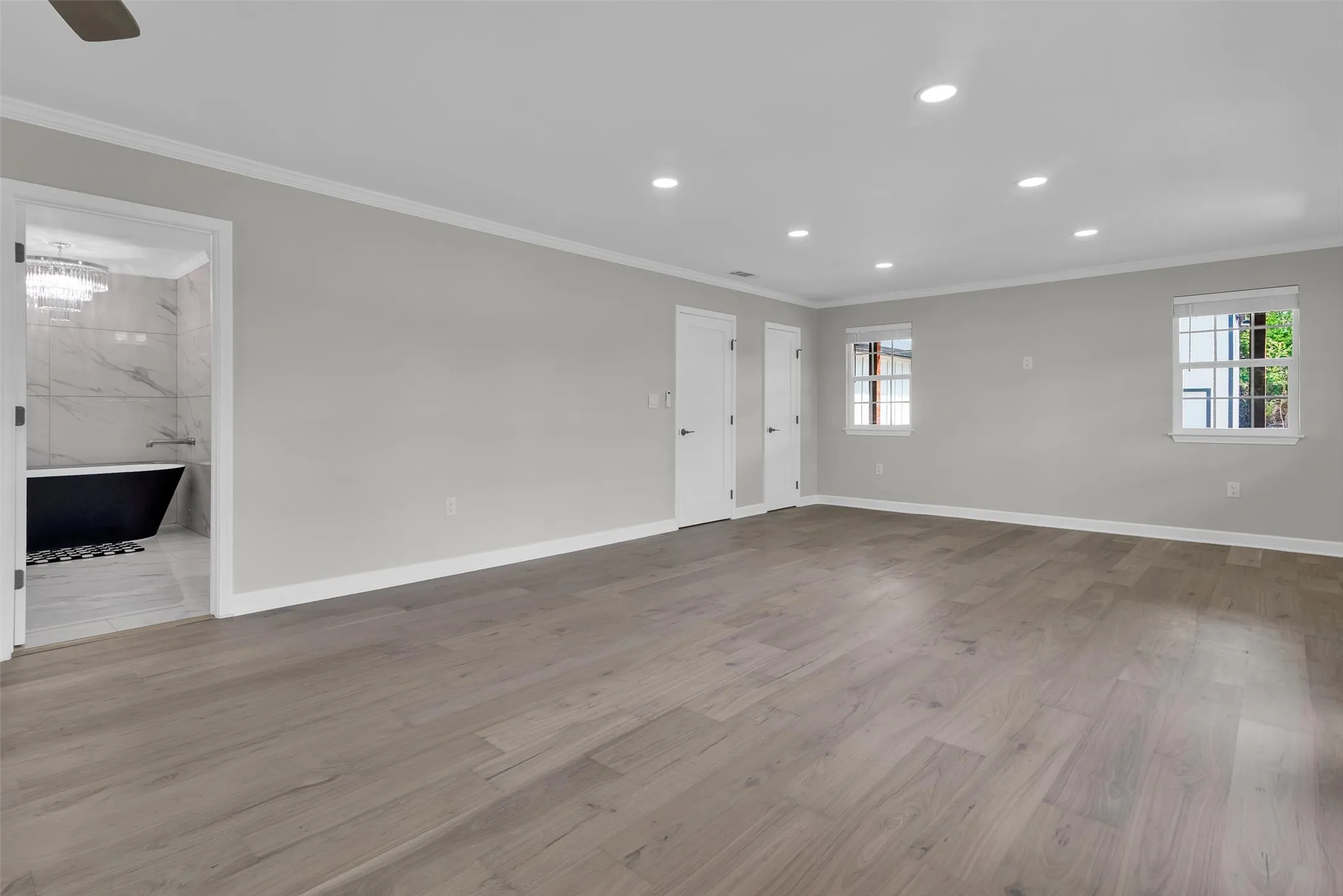 Expansive room featuring wood-finish flooring, recessed lighting, and crisp white trim