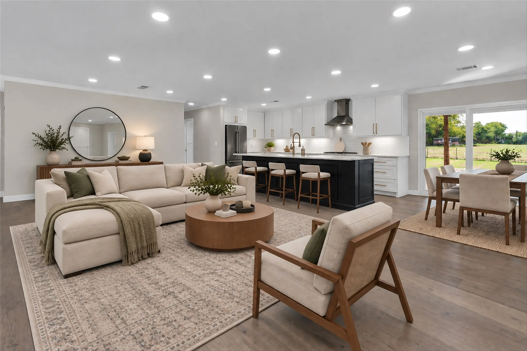 Open-concept living area featuring wood-finish flooring, recessed lighting, and a kitchen with white cabinetry and a contrasting dark island