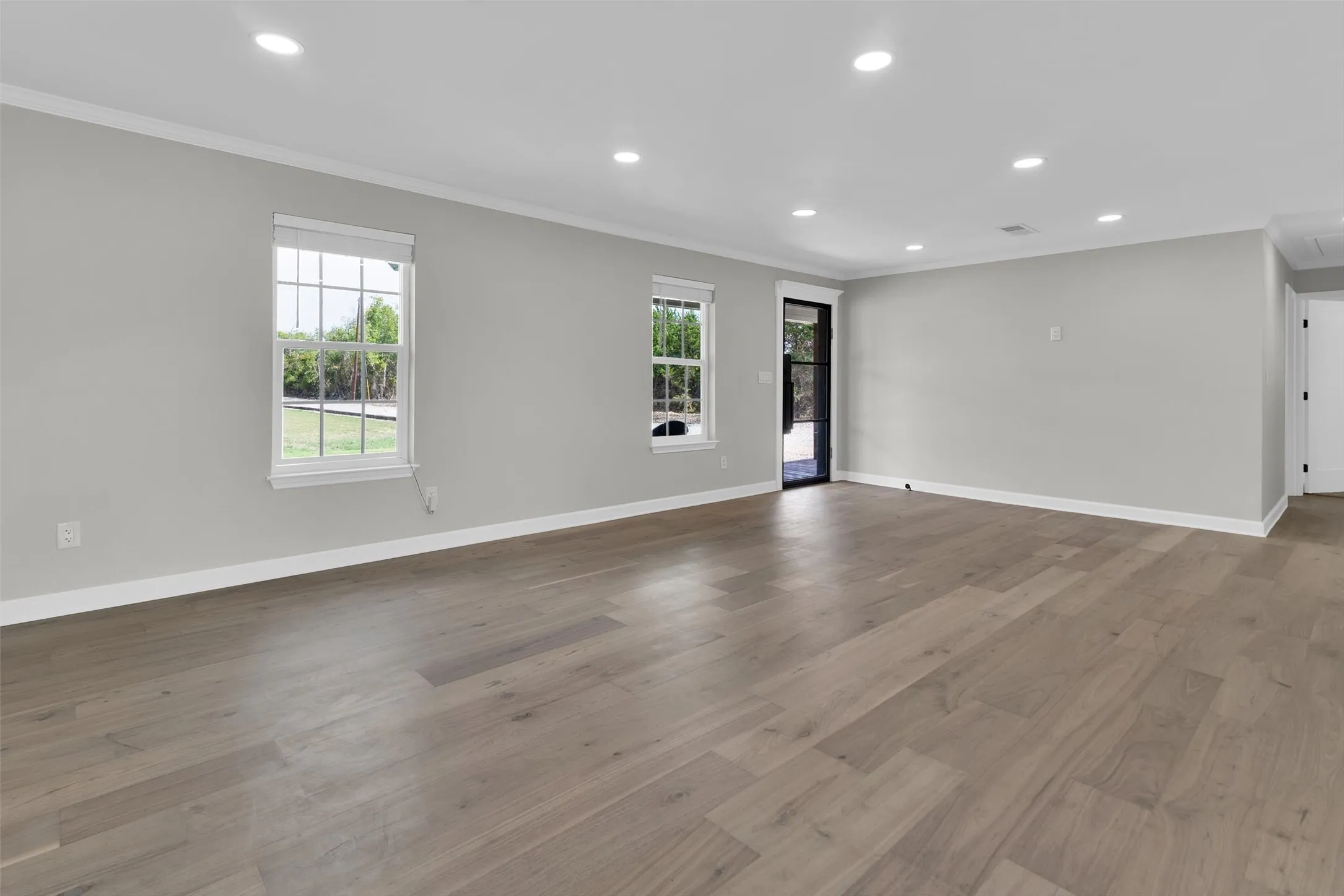 Spacious room featuring wood-finish flooring, recessed lighting, and multiple windows