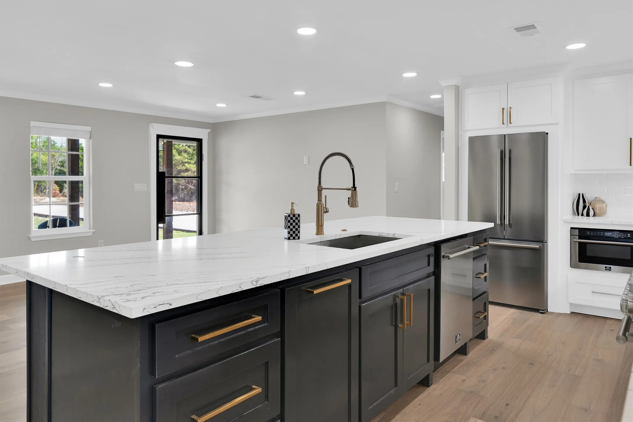 Spacious kitchen island with a white stone countertop, integrated sink, and dark cabinetry