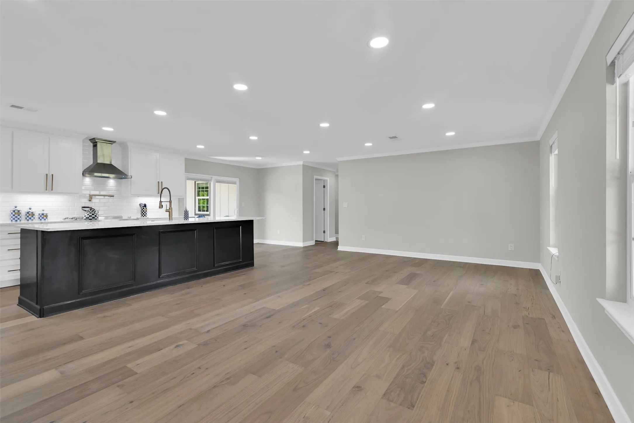 Open-concept living space with wood-finish flooring, recessed lighting, and crown molding