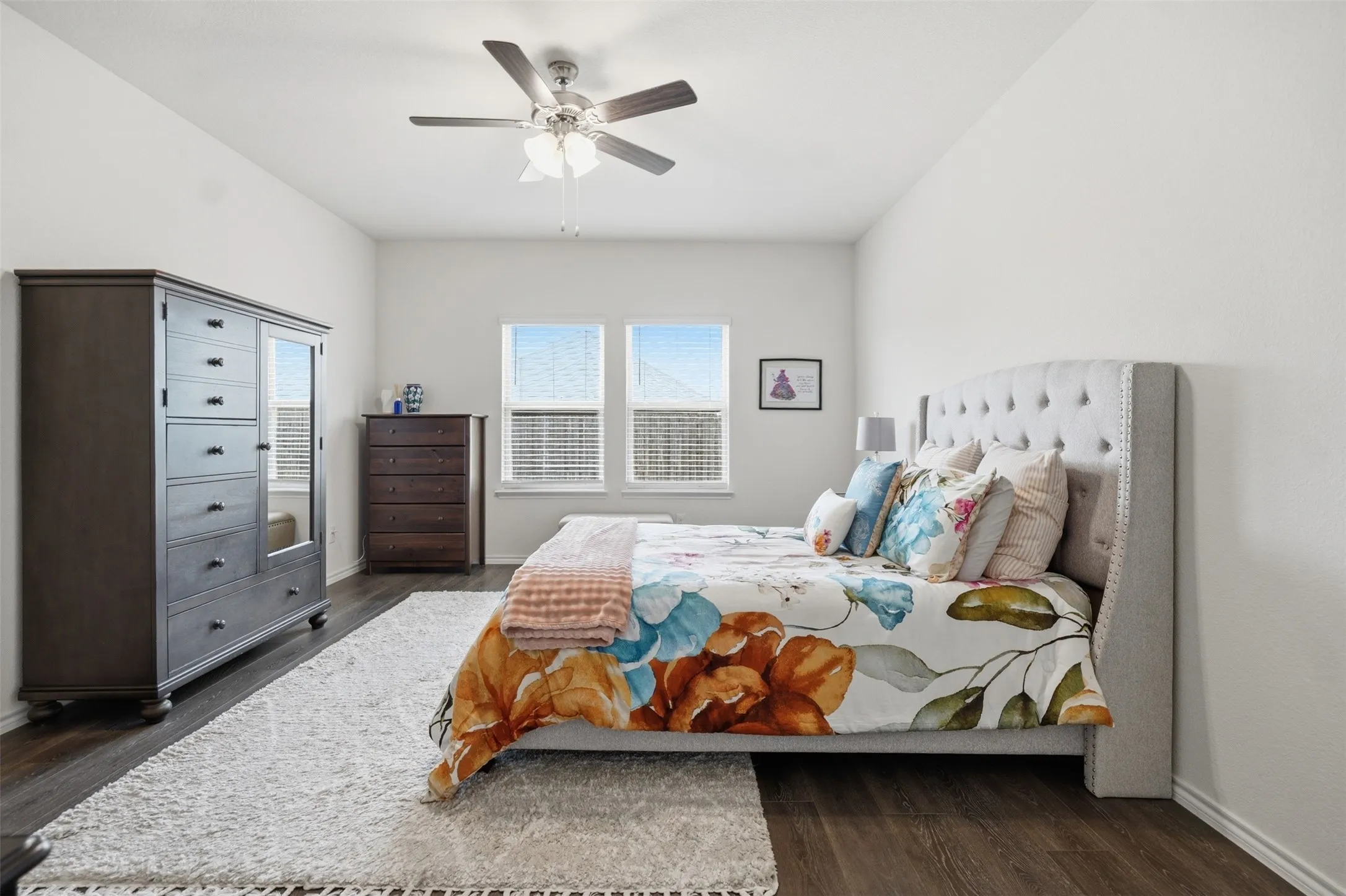 Vaulted ceiling with a ceiling fan, dual windows, and wood-finish flooring