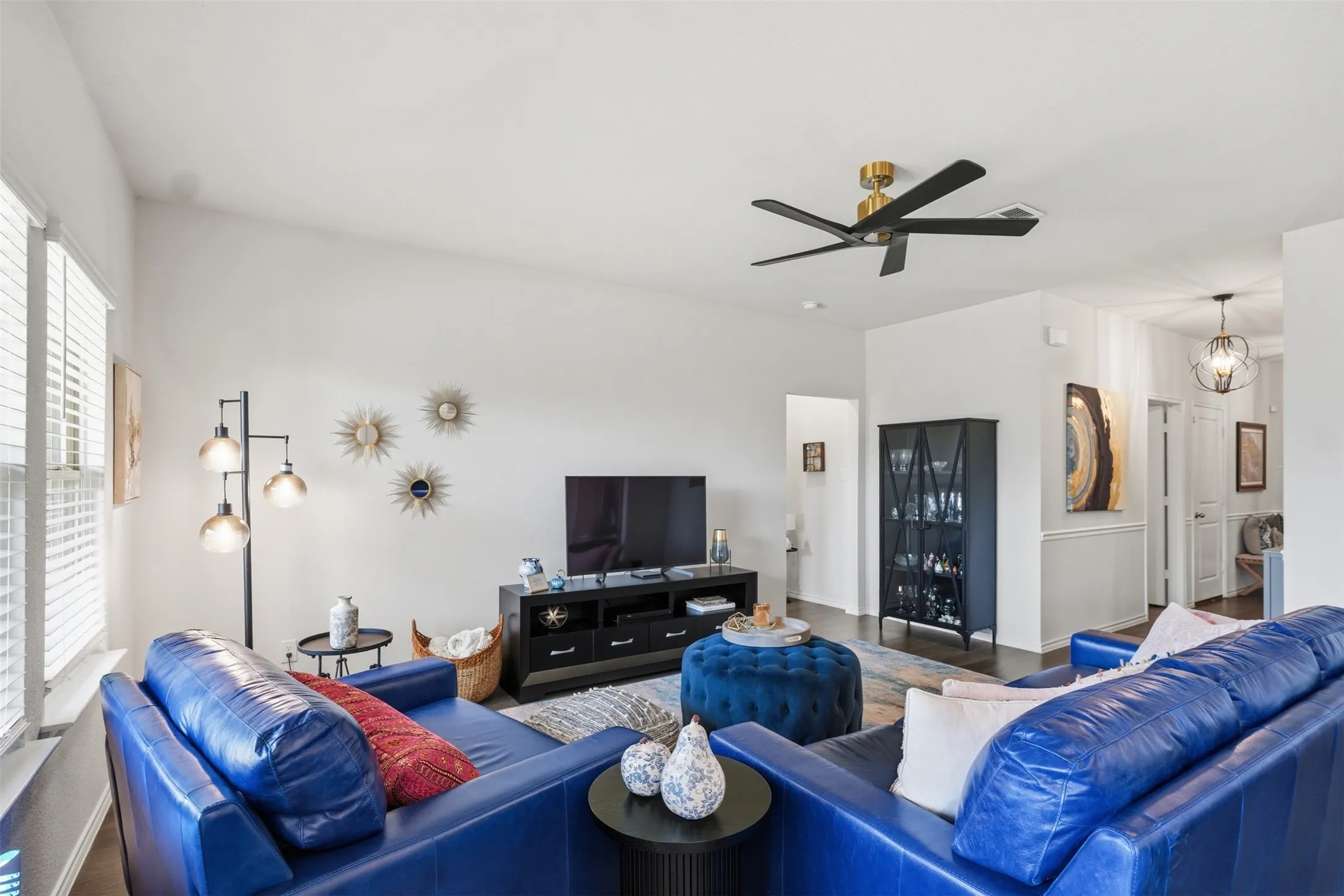 Vaulted ceiling with a black and gold ceiling fan, white window blinds, dark wood-finish flooring, and white wall finishes