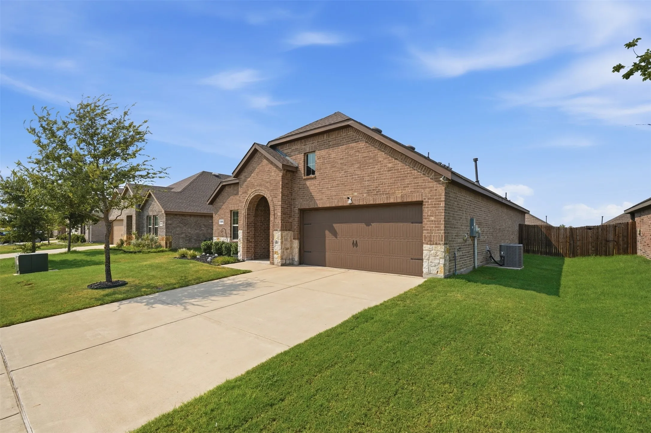 Brick exterior with stone accents, arched entryway, attached garage, and a concrete driveway