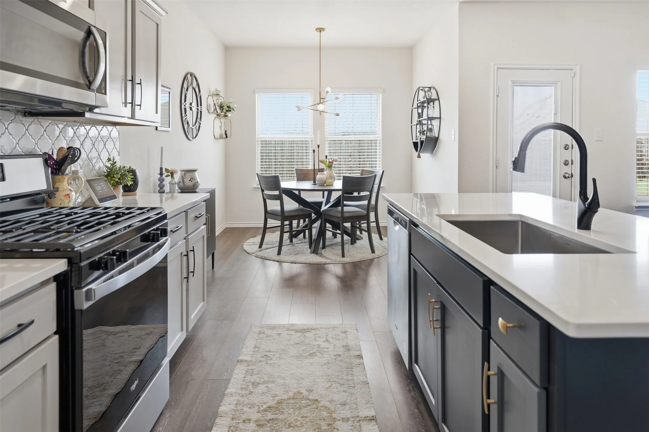 Modern kitchen featuring light cabinetry, stainless steel appliances, white countertops, and wood-finish flooring