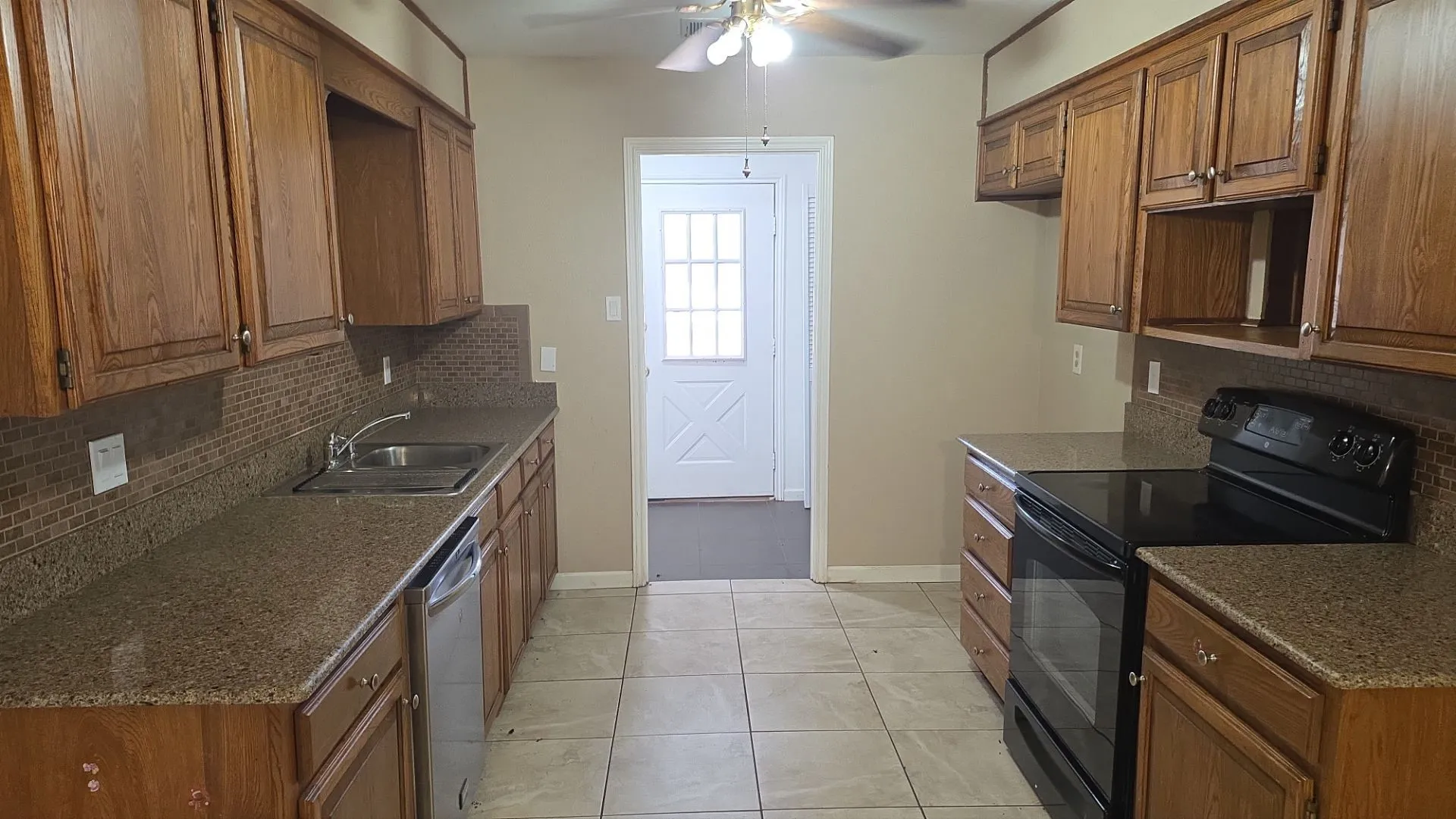Kitchen featuring wood cabinetry, granite-style countertops, mosaic tile backsplash, and a ceramic tile floor