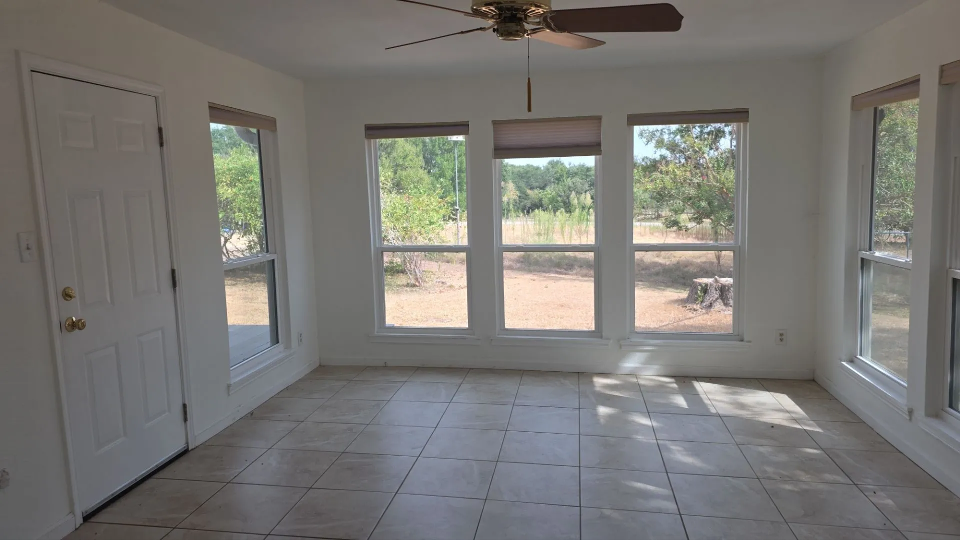 Tile flooring, multiple large windows, ceiling fan, and white paneled door