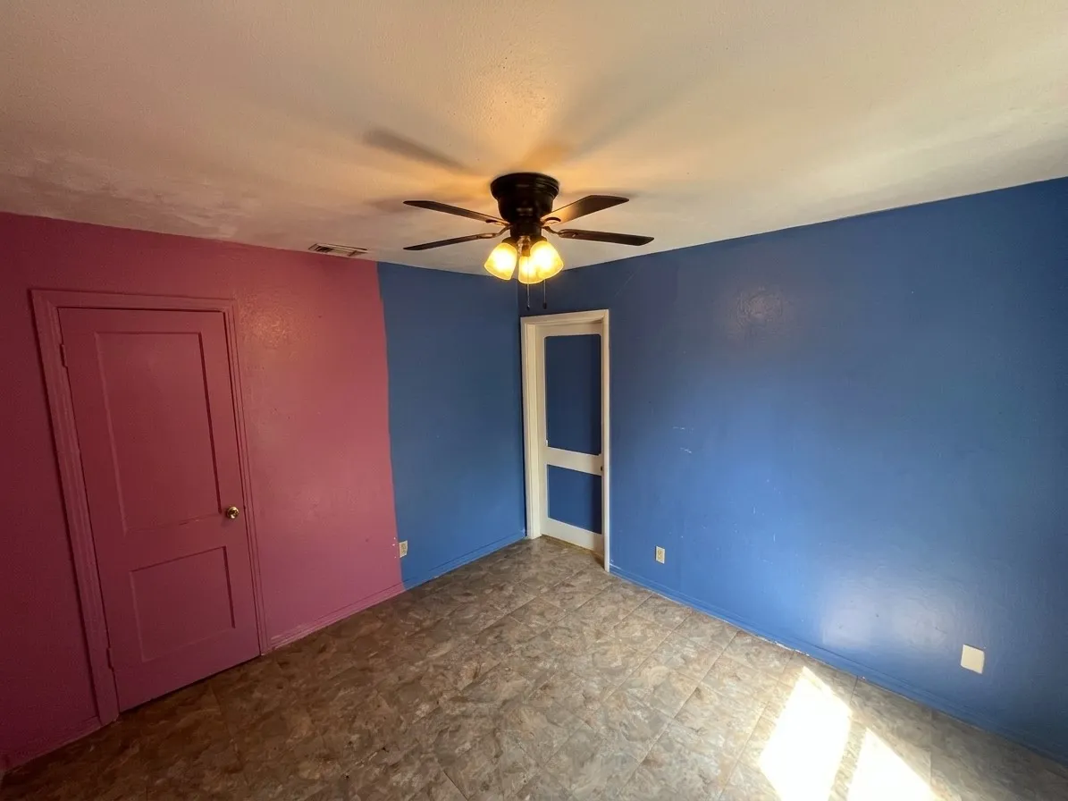Room featuring a ceiling fan with integrated lighting, two panel doors, and neutral-toned flooring