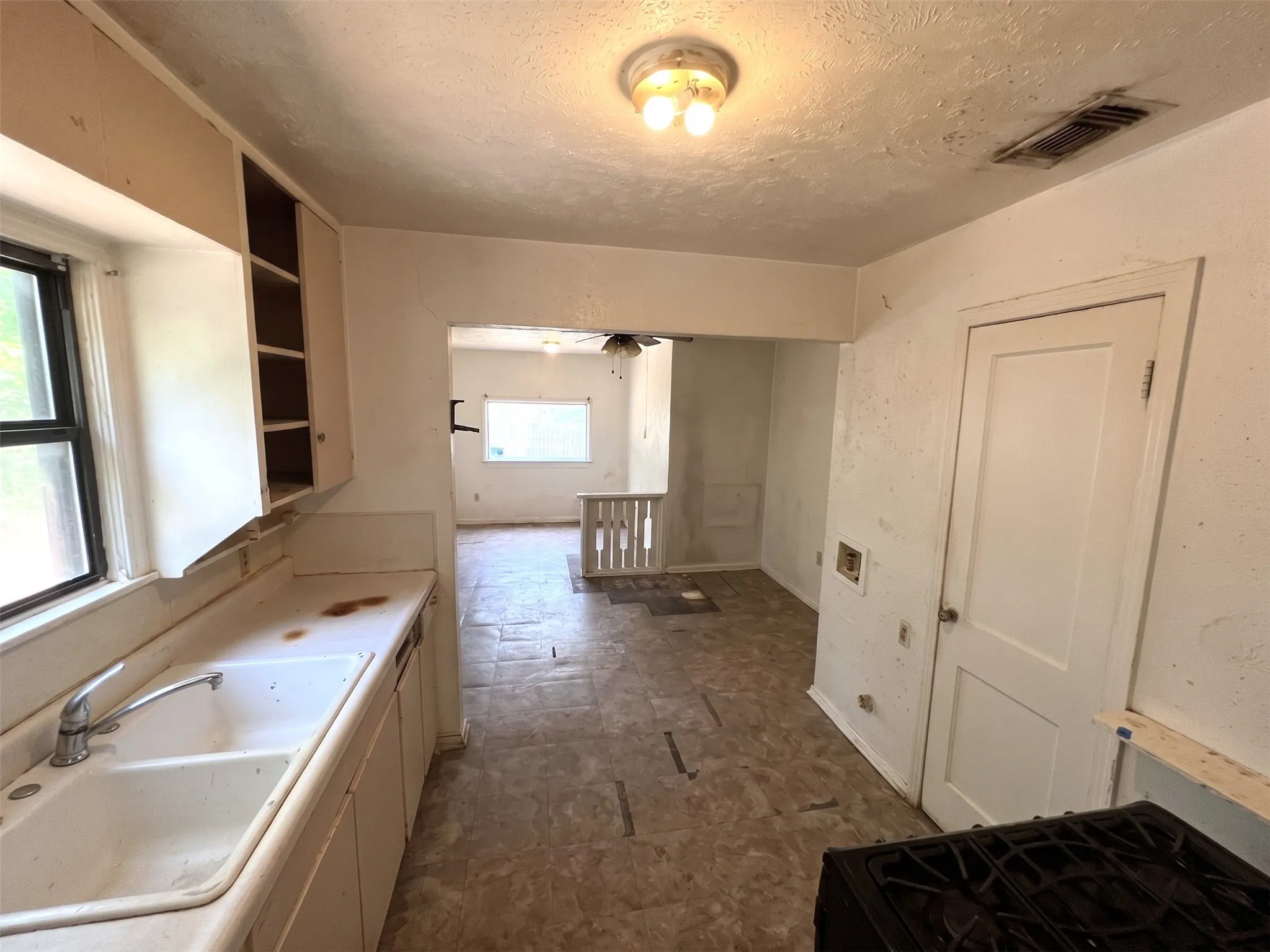 Kitchen area featuring a double basin sink, upper and lower cabinetry, and a window