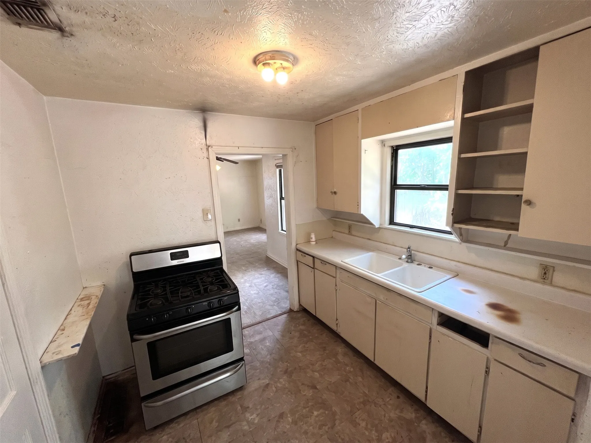 Kitchen featuring a stainless steel gas range, dual basin sink, and upper and lower cabinetry
