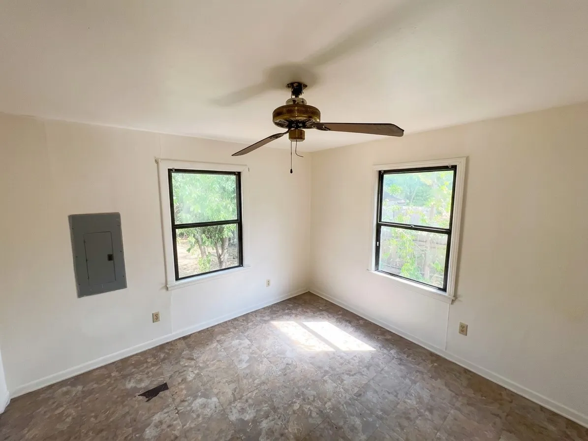 Ceiling fan fixture and two windows with dark trim, set within light-toned walls