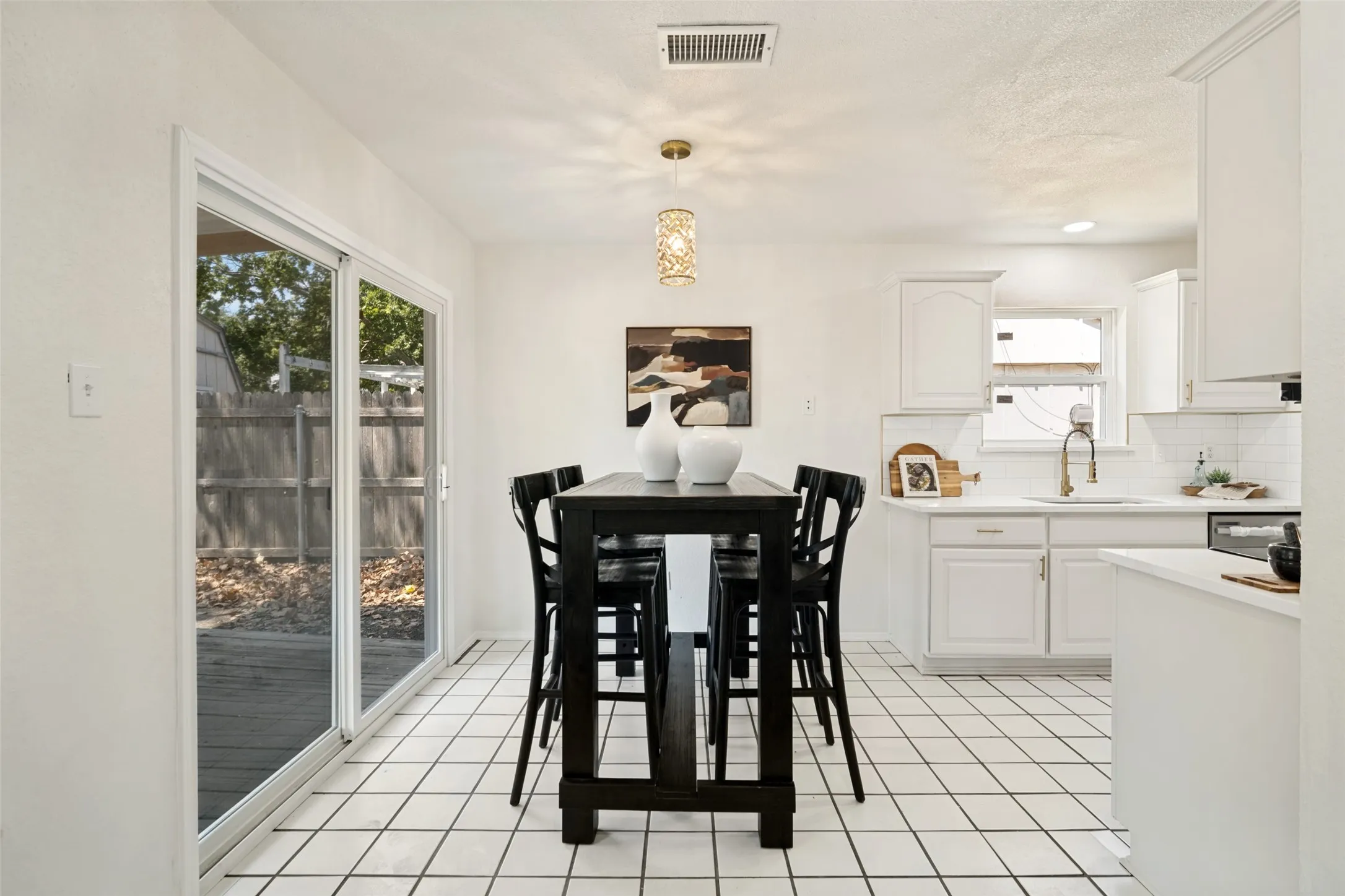 White tile flooring, white shaker cabinetry, white countertops, built-in dishwasher, and sliding glass door