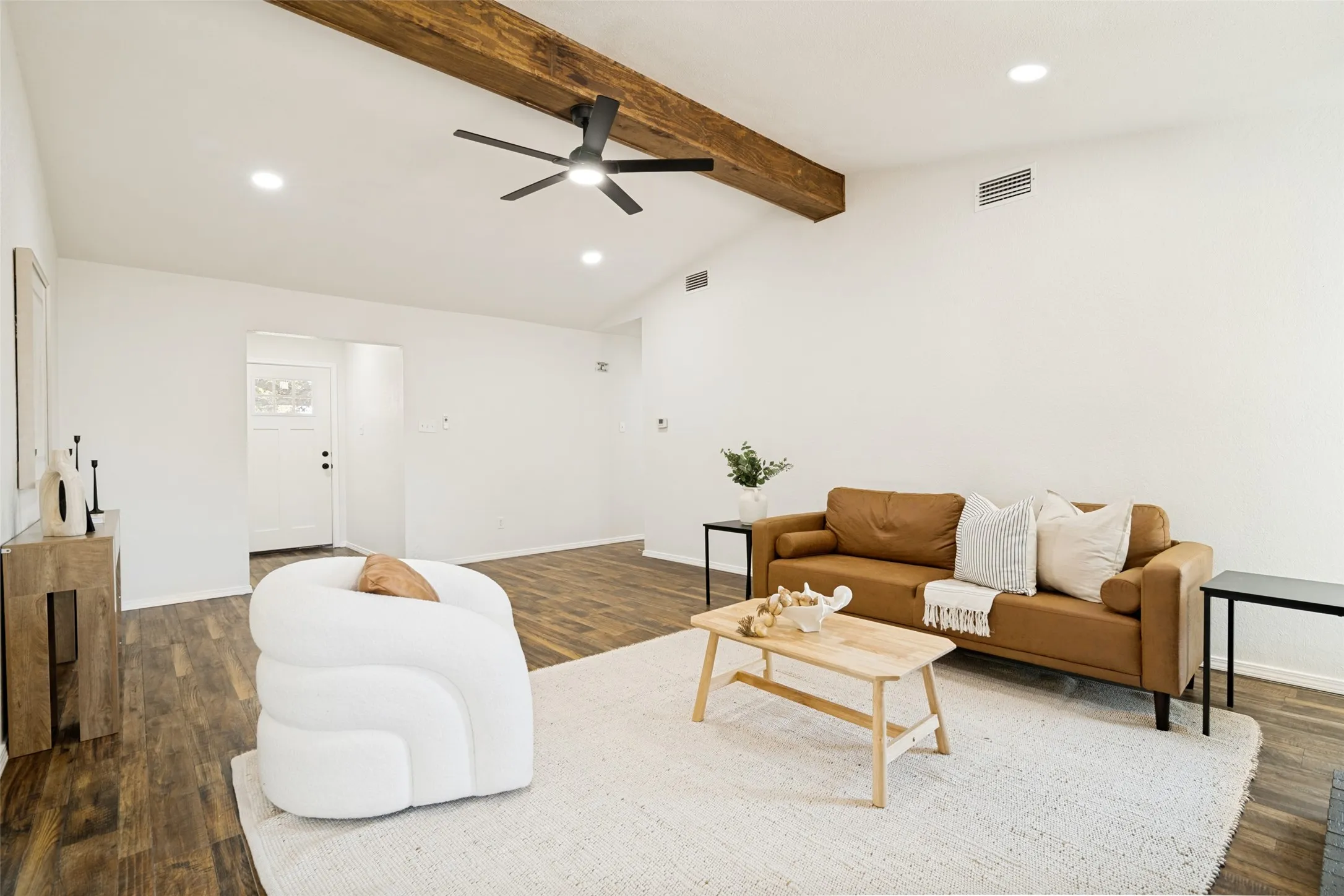 Vaulted ceiling with exposed wood beam, wood-finish flooring, recessed lighting, and a front entry door with decorative glass