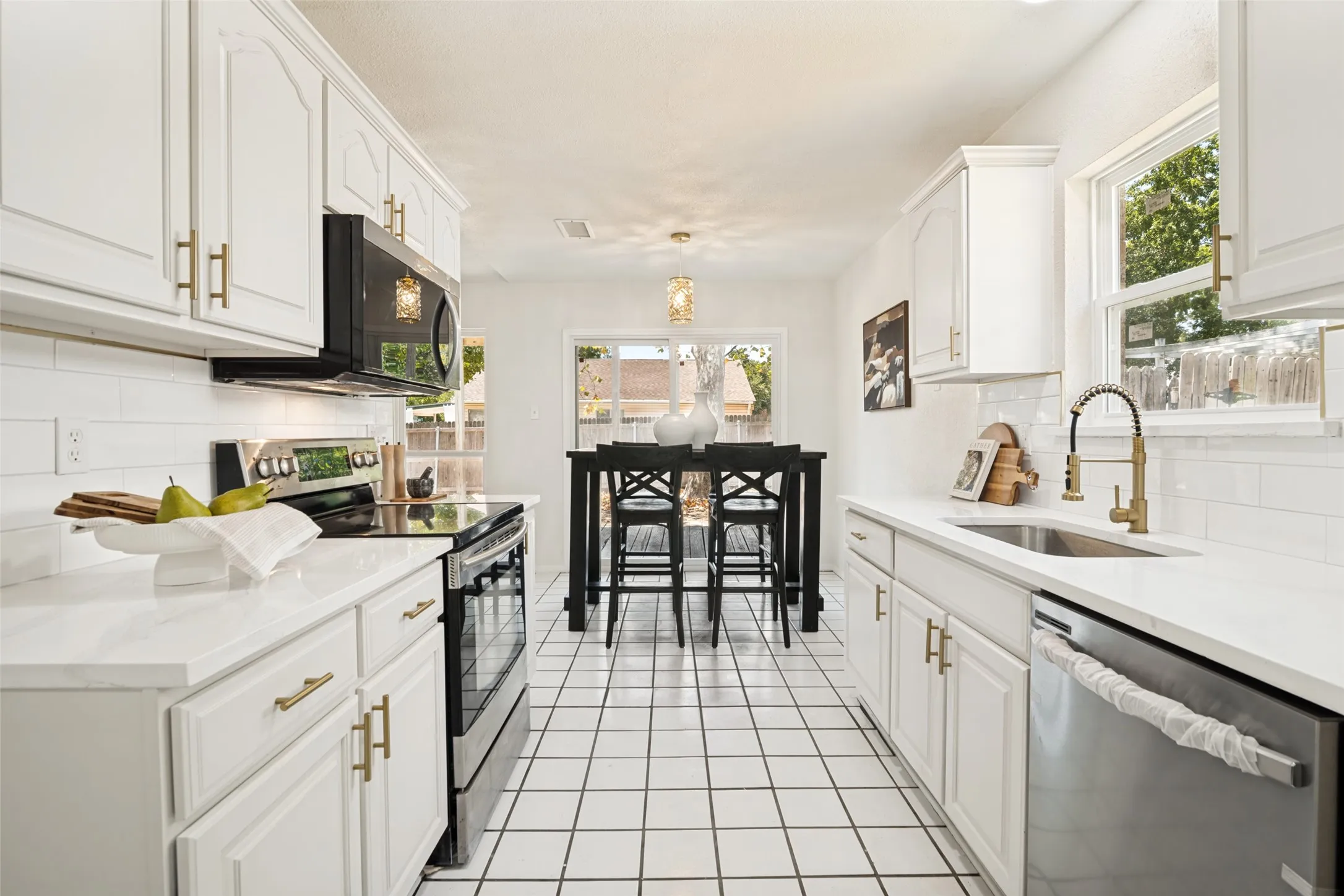 Galley kitchen featuring white cabinetry, light-toned countertops, a subway tile backsplash, and tile flooring