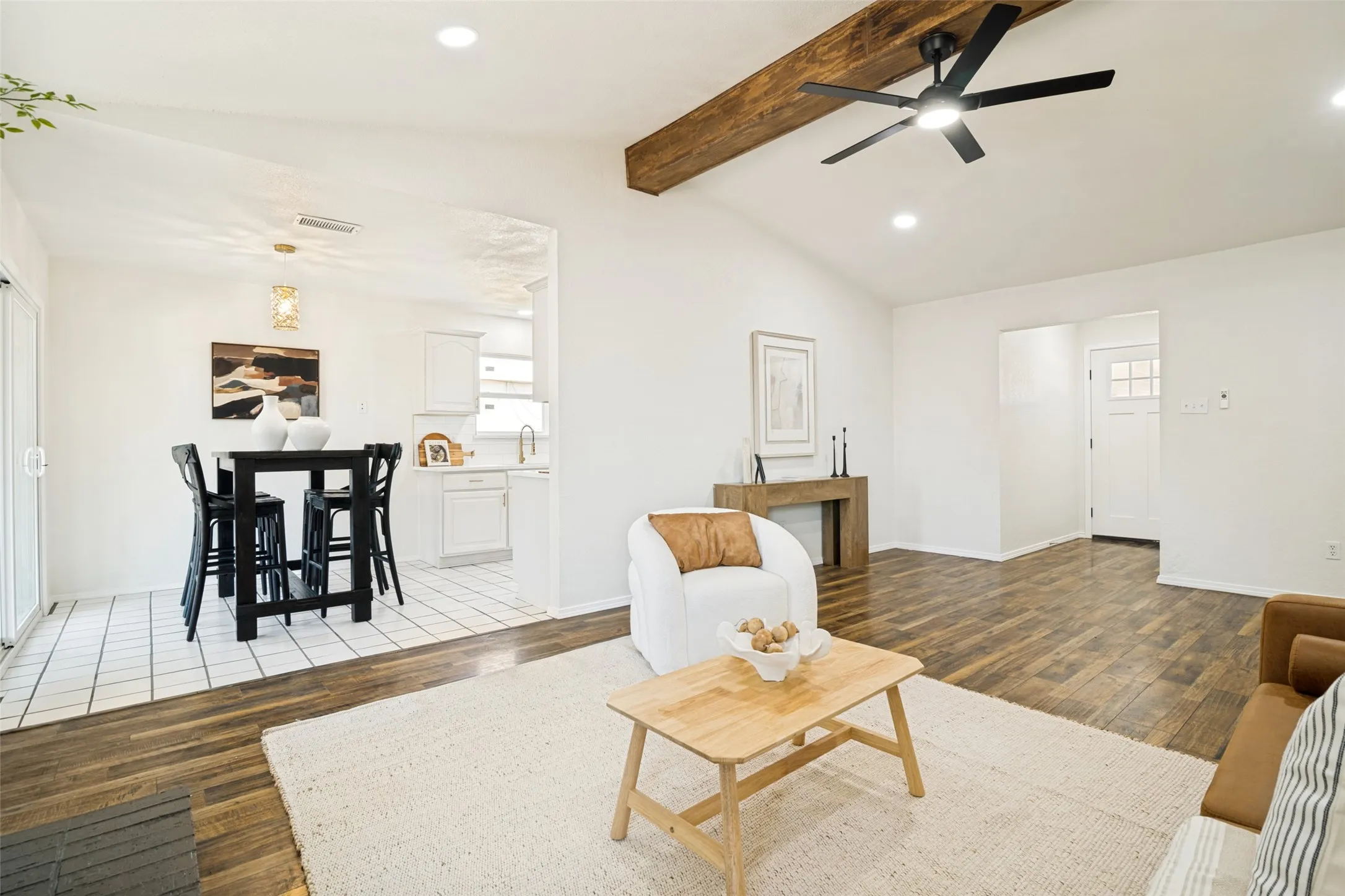 Vaulted ceiling with exposed wood beam, wood-finish flooring, recessed lighting, and a modern ceiling fan