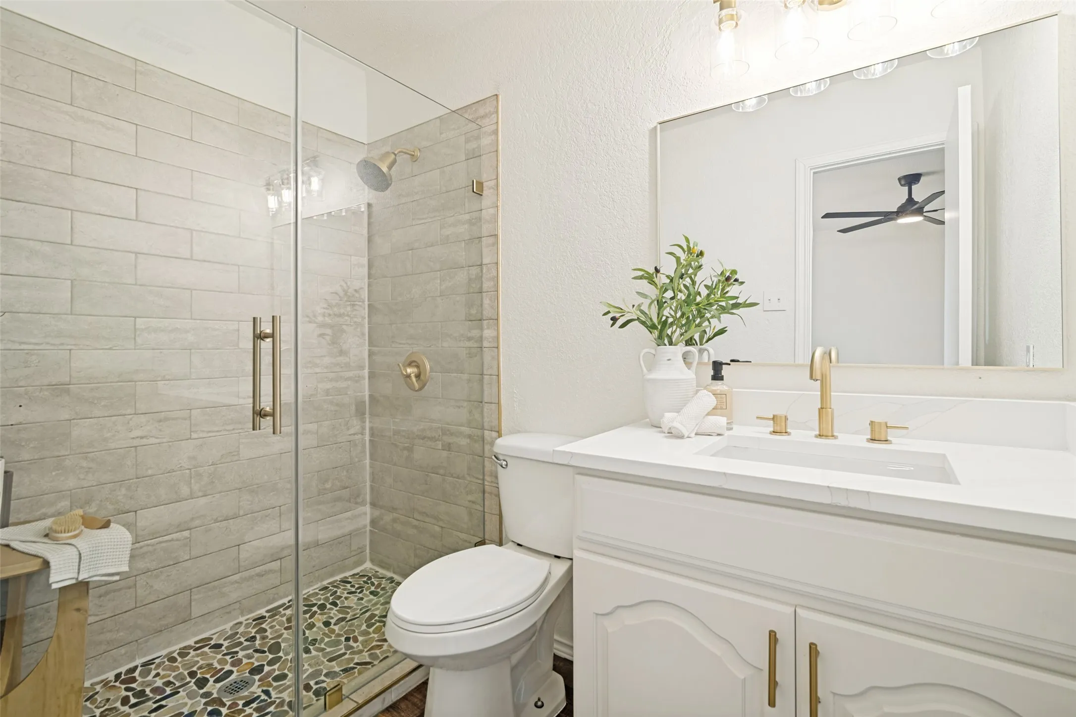 Glass-enclosed shower with horizontal tile surround and pebble flooring