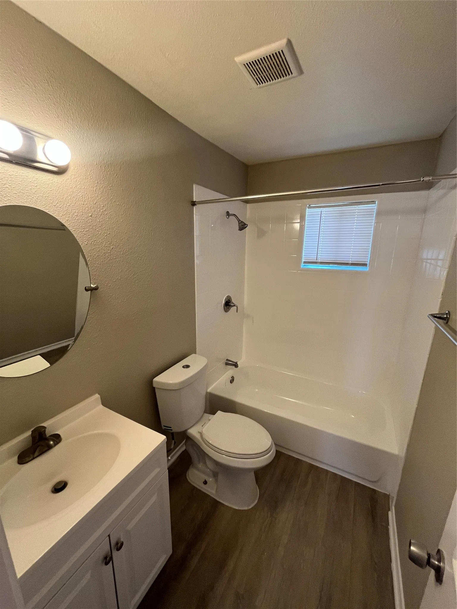 Bathroom featuring a vanity with integrated sink, wood-finish flooring, and a white tub with shower