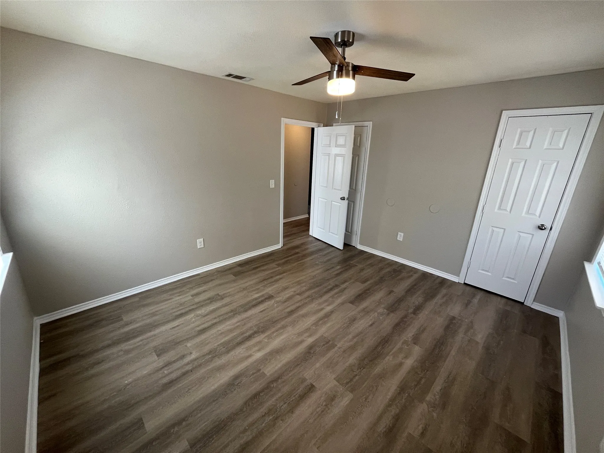 Neutral-toned walls, wood-finish flooring, white trim, and a ceiling fan with integrated lighting