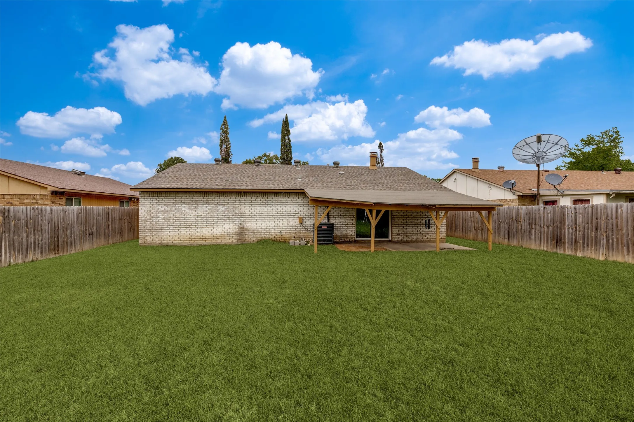 Large backyard complete with full wood fencing and a covered patio with wood beams