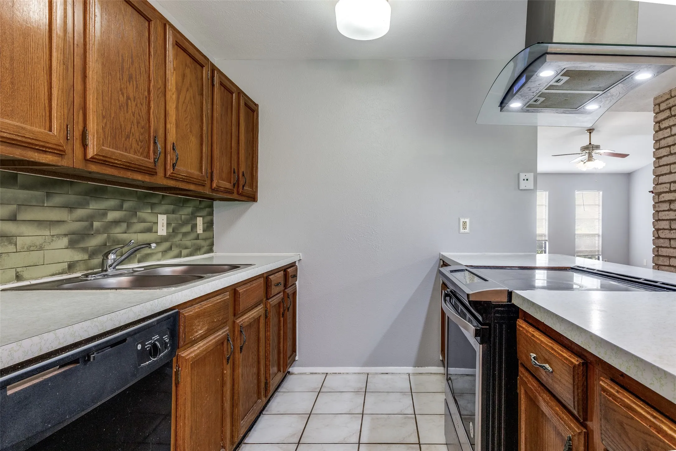 Kitchen featuring wood cabinetry, a double basin sink, tile flooring, and a stainless steel range hood