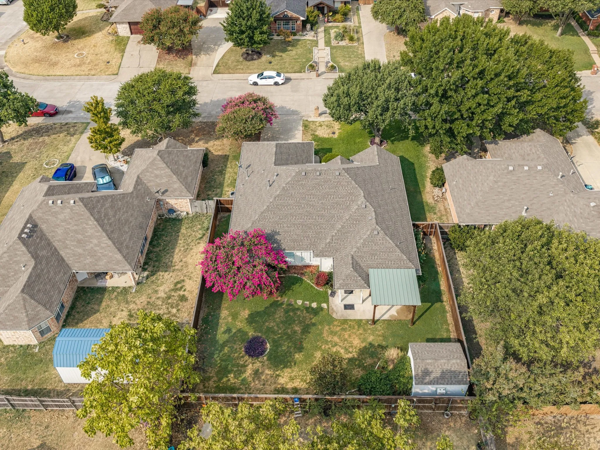 Fenced backyard with a covered patio, detached storage shed, and mature landscaping