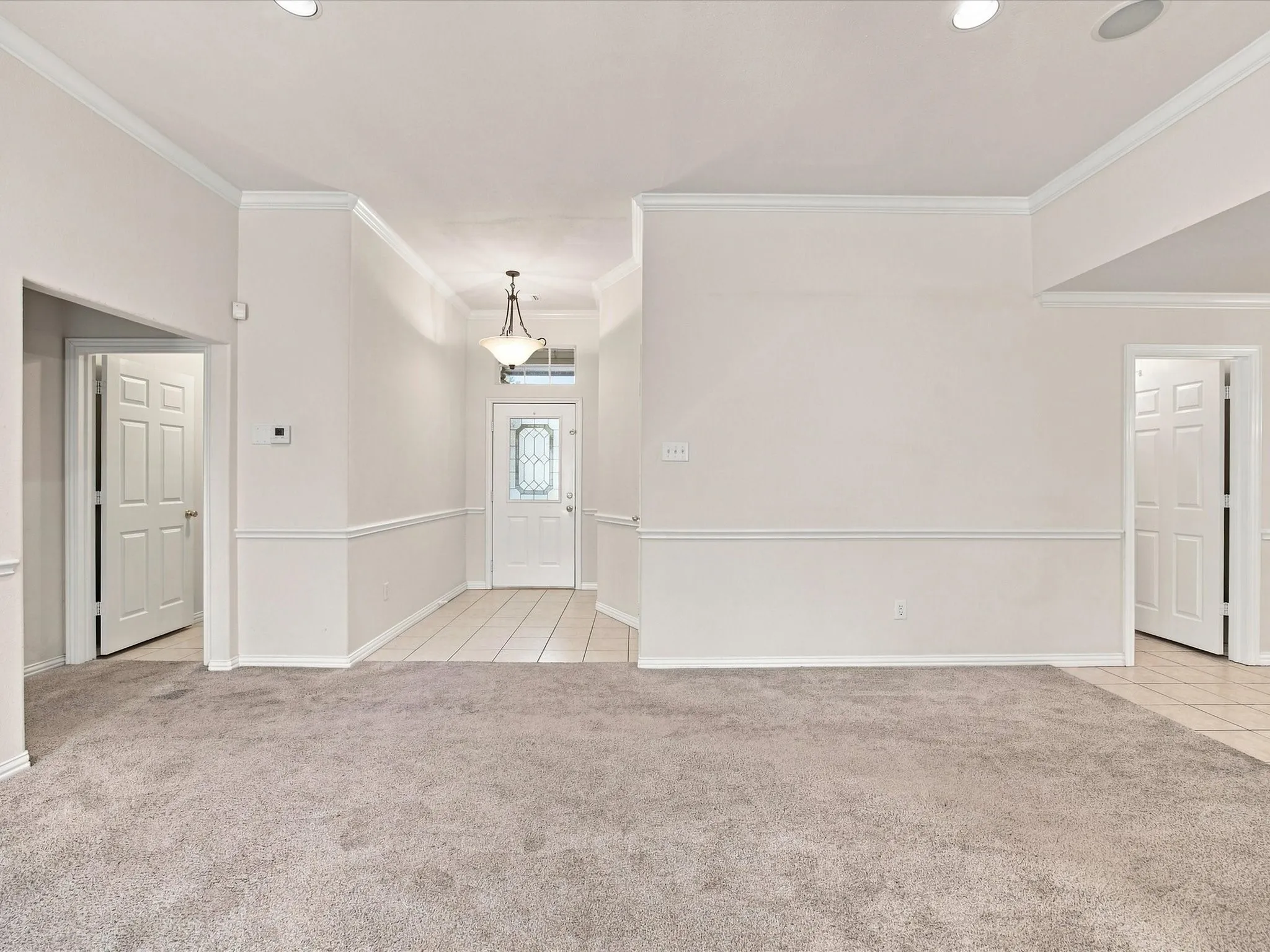 Recessed ceiling lighting, crown molding, chair rail molding, tiled entryway, and four-panel interior doors