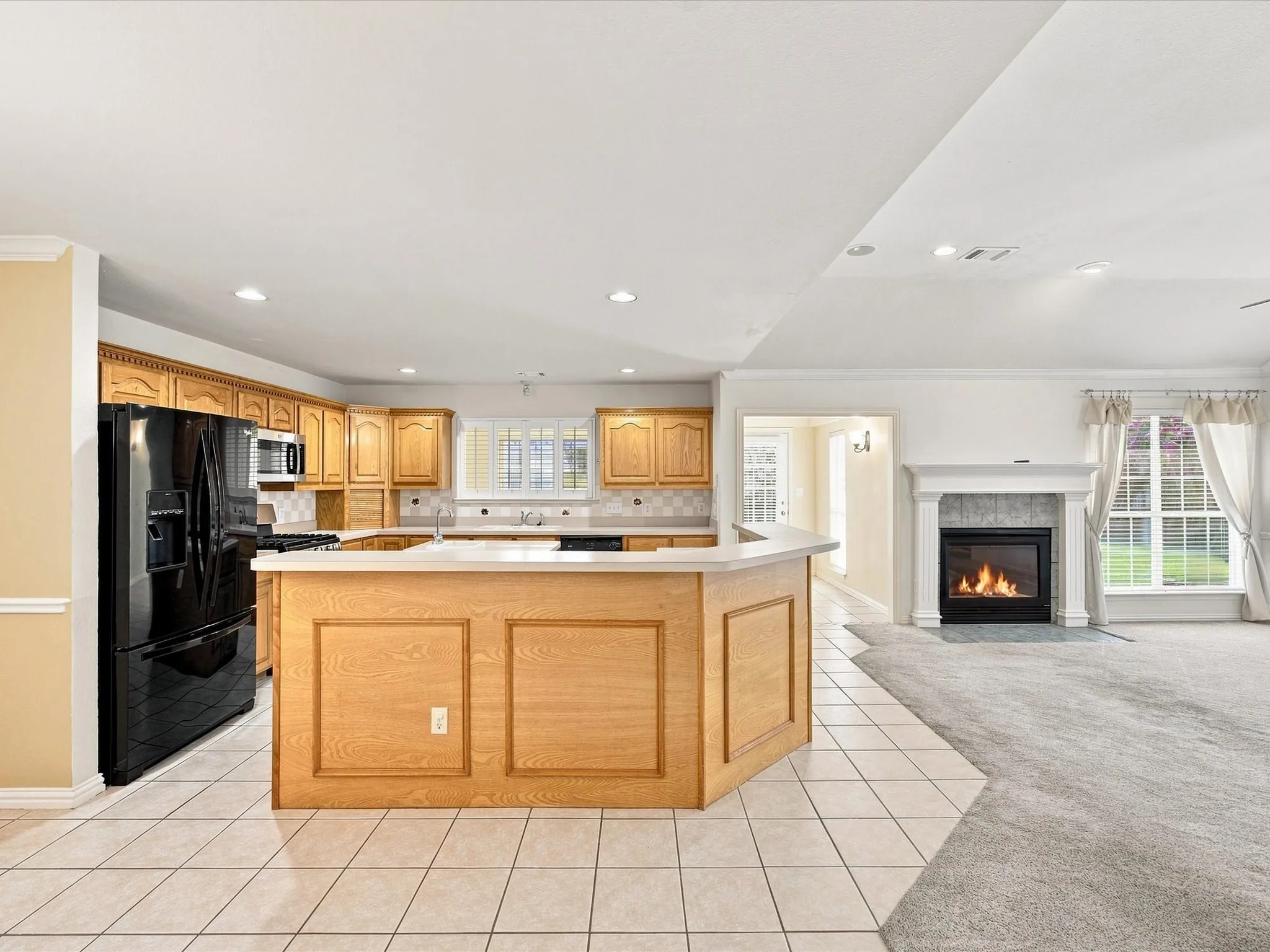 Kitchen island with wood paneling, wood-finish cabinetry, tile flooring, and a fireplace with a mantel