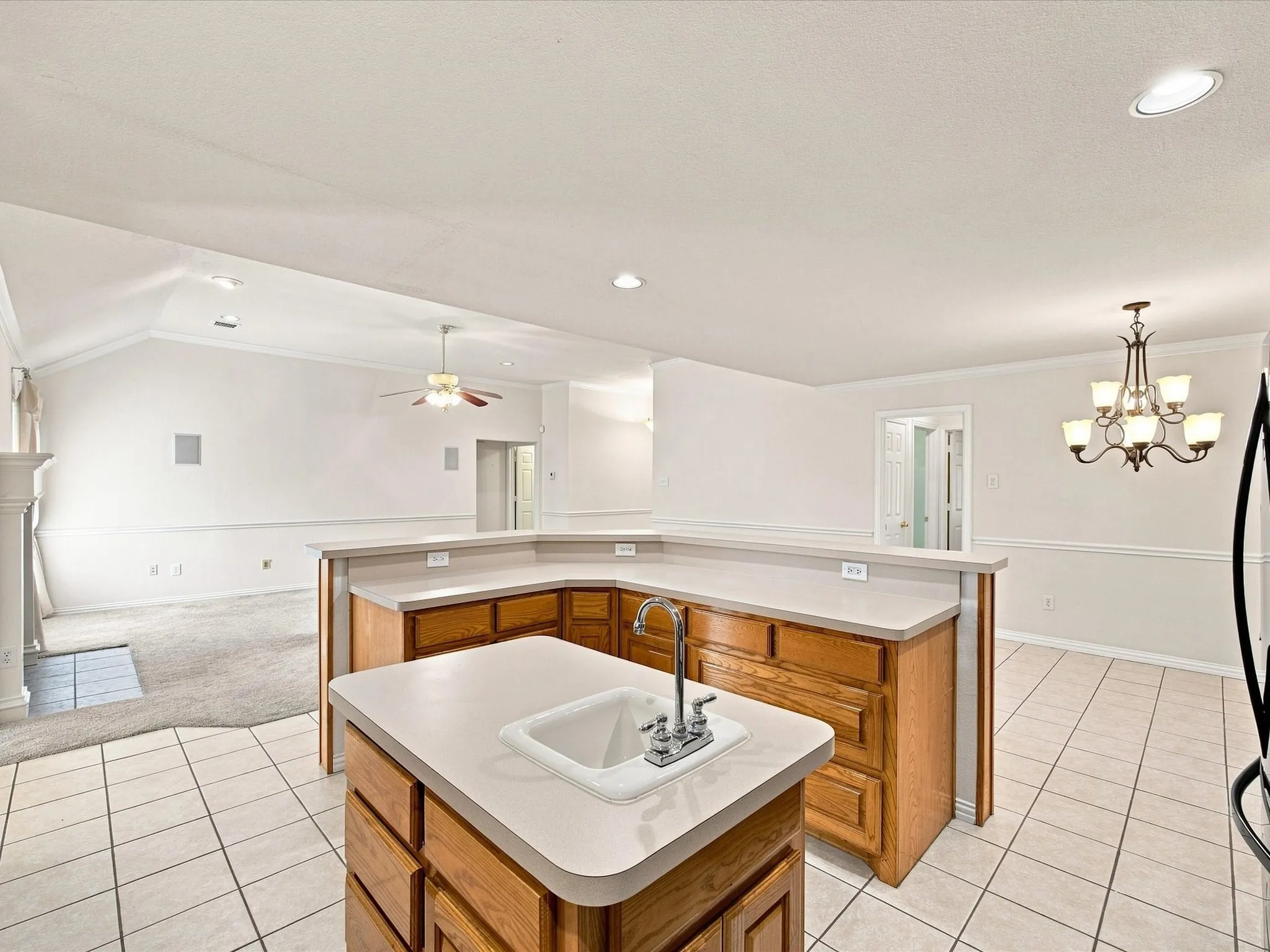 Kitchen island with integrated sink, wood cabinetry, and light-toned countertops