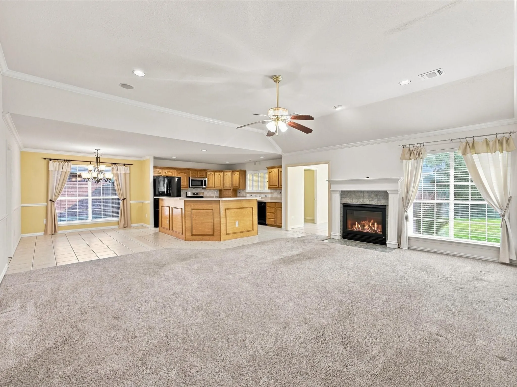 Expansive open-concept living space with a gas fireplace, a ceiling fan, and recessed lighting