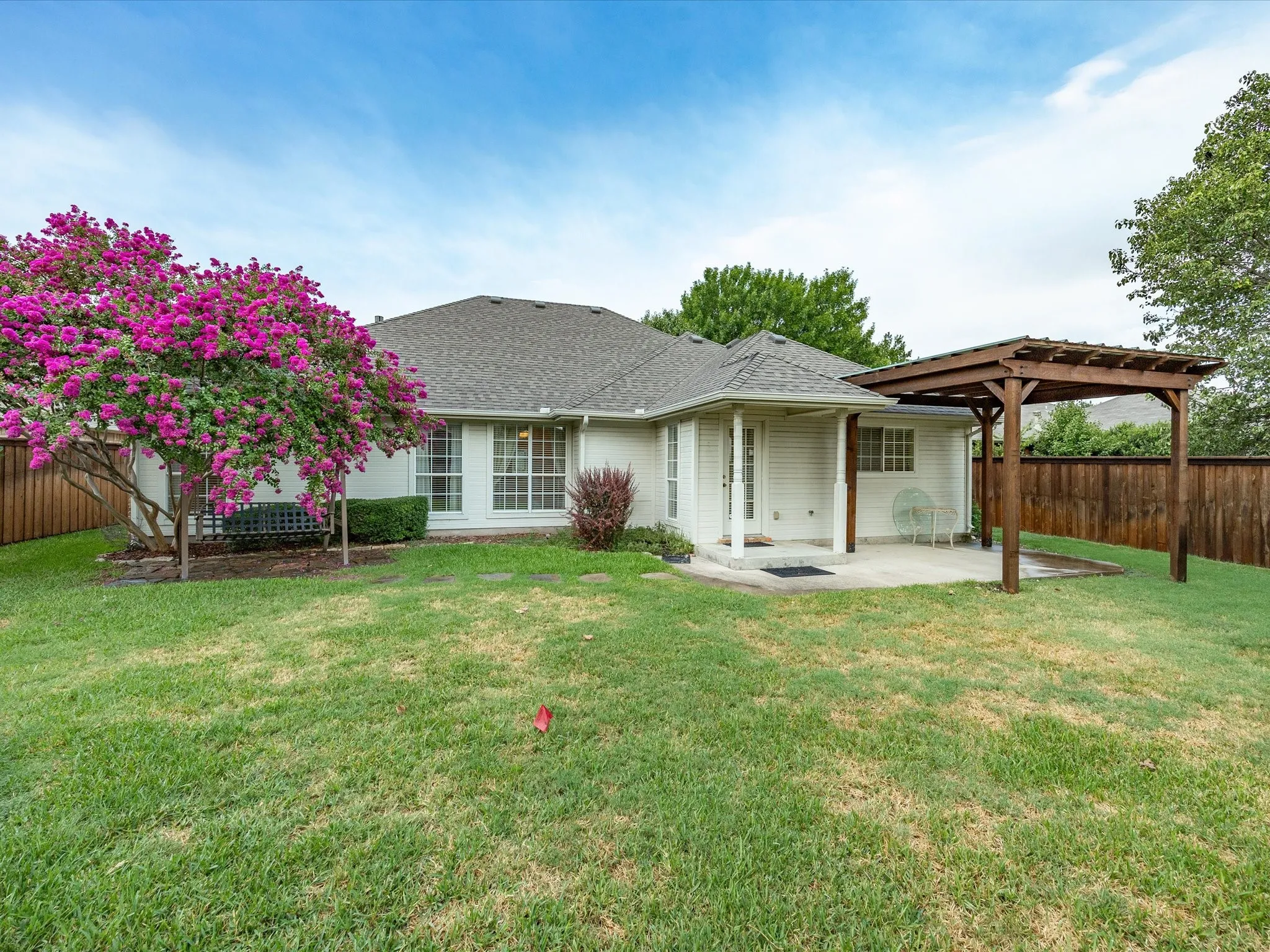 Expansive backyard featuring a lush lawn, privacy fencing, a covered patio, and a wood pergola