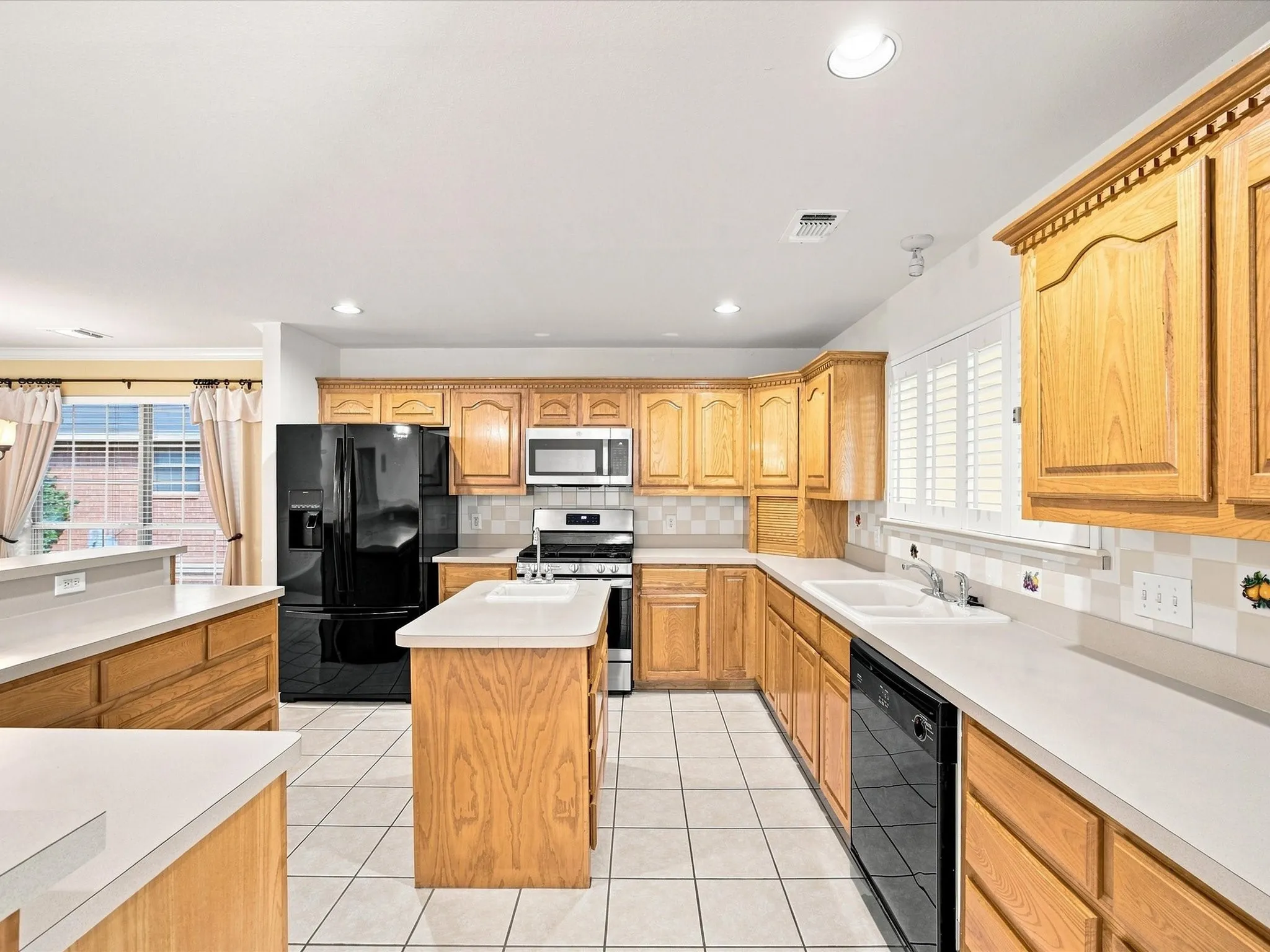 Kitchen featuring wood cabinetry, white tile flooring, white countertops, and stainless steel appliances