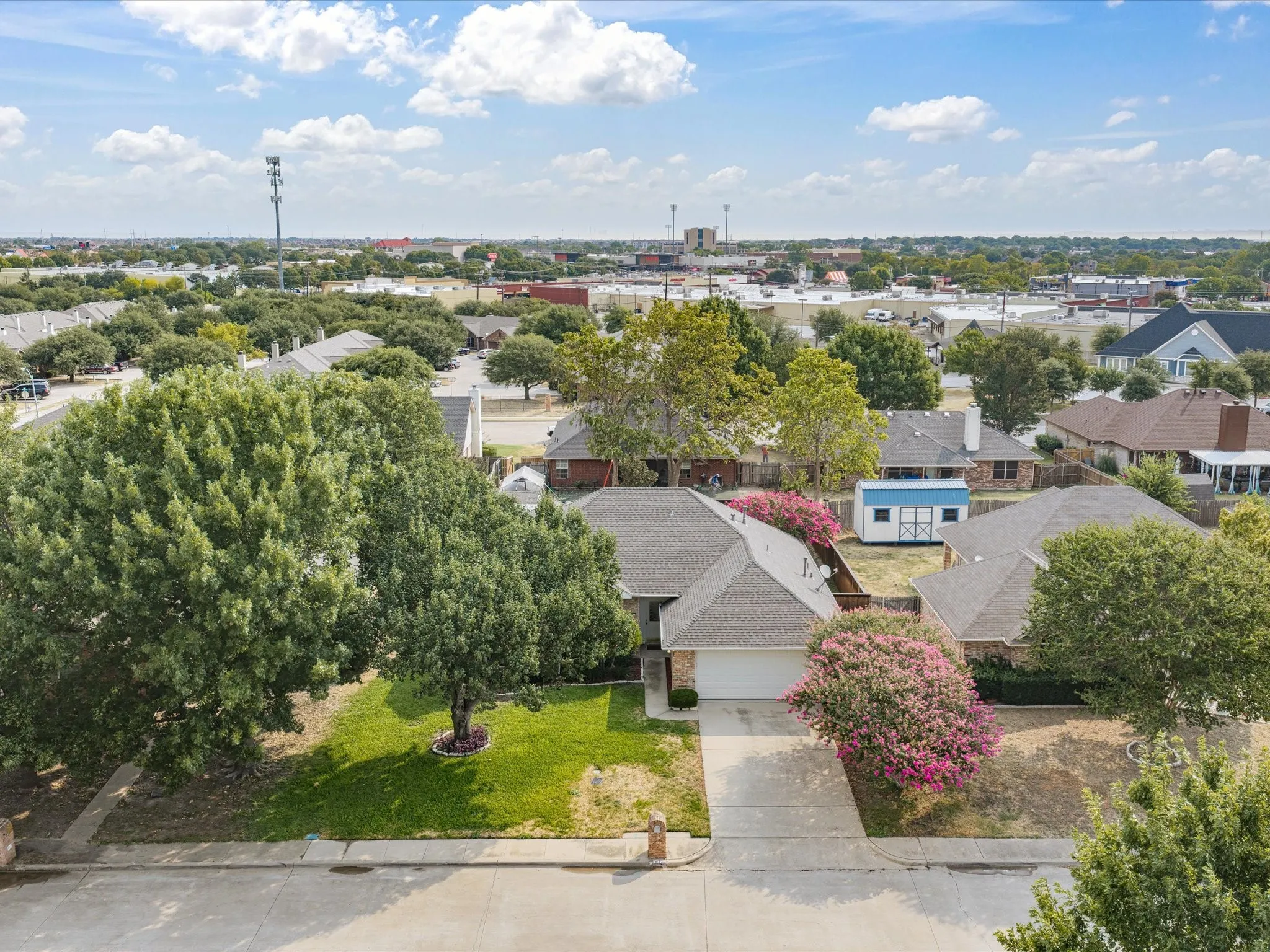 Gabled roofline, attached two-car garage, concrete driveway, front lawn, and mature landscaping
