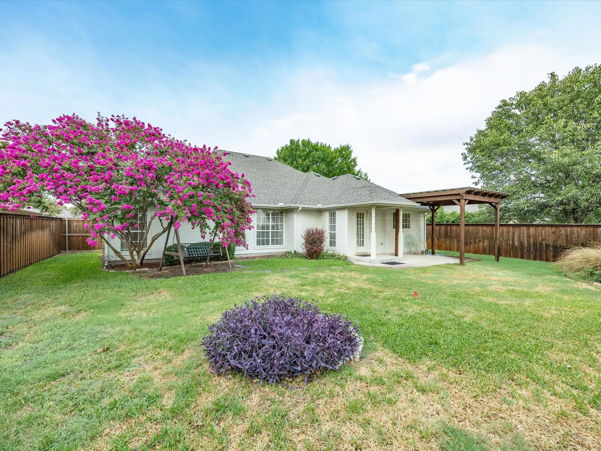 Spacious backyard with a wood privacy fence, concrete patio, and a wood pergola