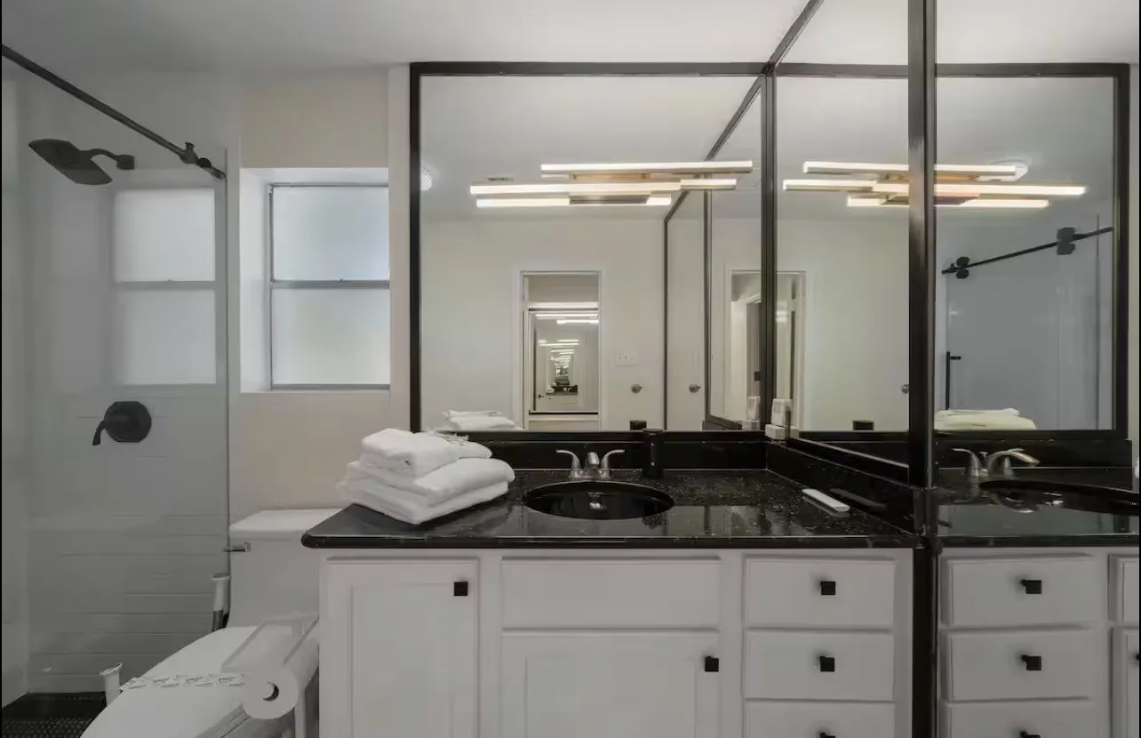 Bathroom featuring a white vanity with black hardware, black countertop, and an integrated sink
