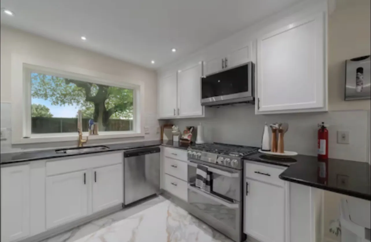 White shaker-style cabinetry, dark countertops, stainless steel appliances, recessed lighting, and patterned flooring