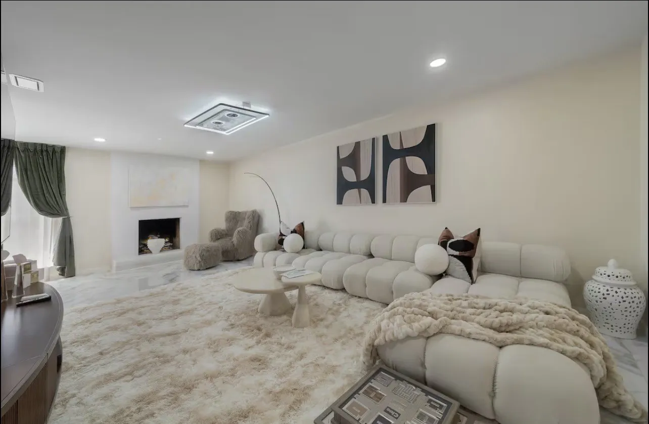 Recessed lighting, fireplace with a white mantel, wide window with drapery, and a contemporary ceiling fixture