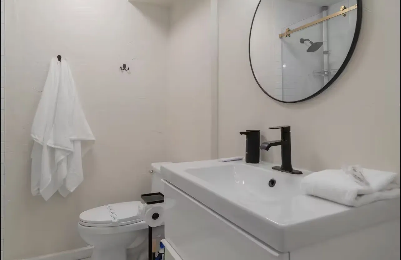 Vanity with integrated sink, matte black faucet, and circular mirror
