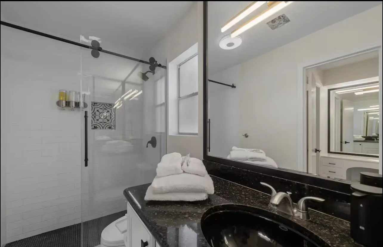 Glass-enclosed shower with a sliding barn door fixture and white subway tile surround