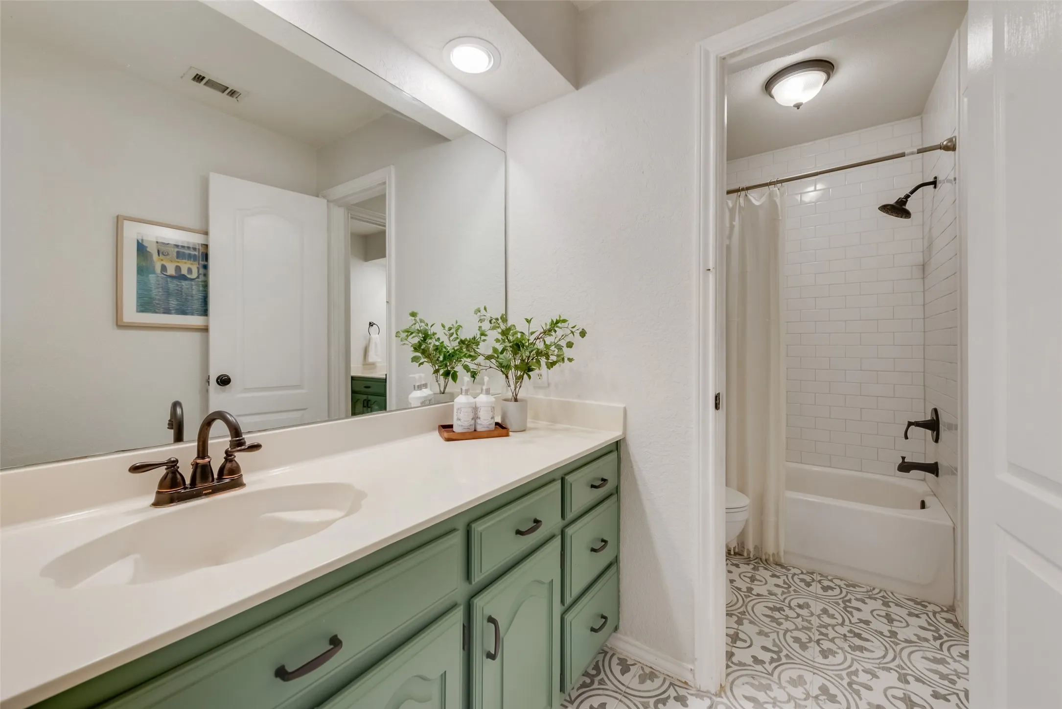 Pretty vanity connected to bedroom 2. Peek the pretty tiled floors and subway tiled shower/tub combo.