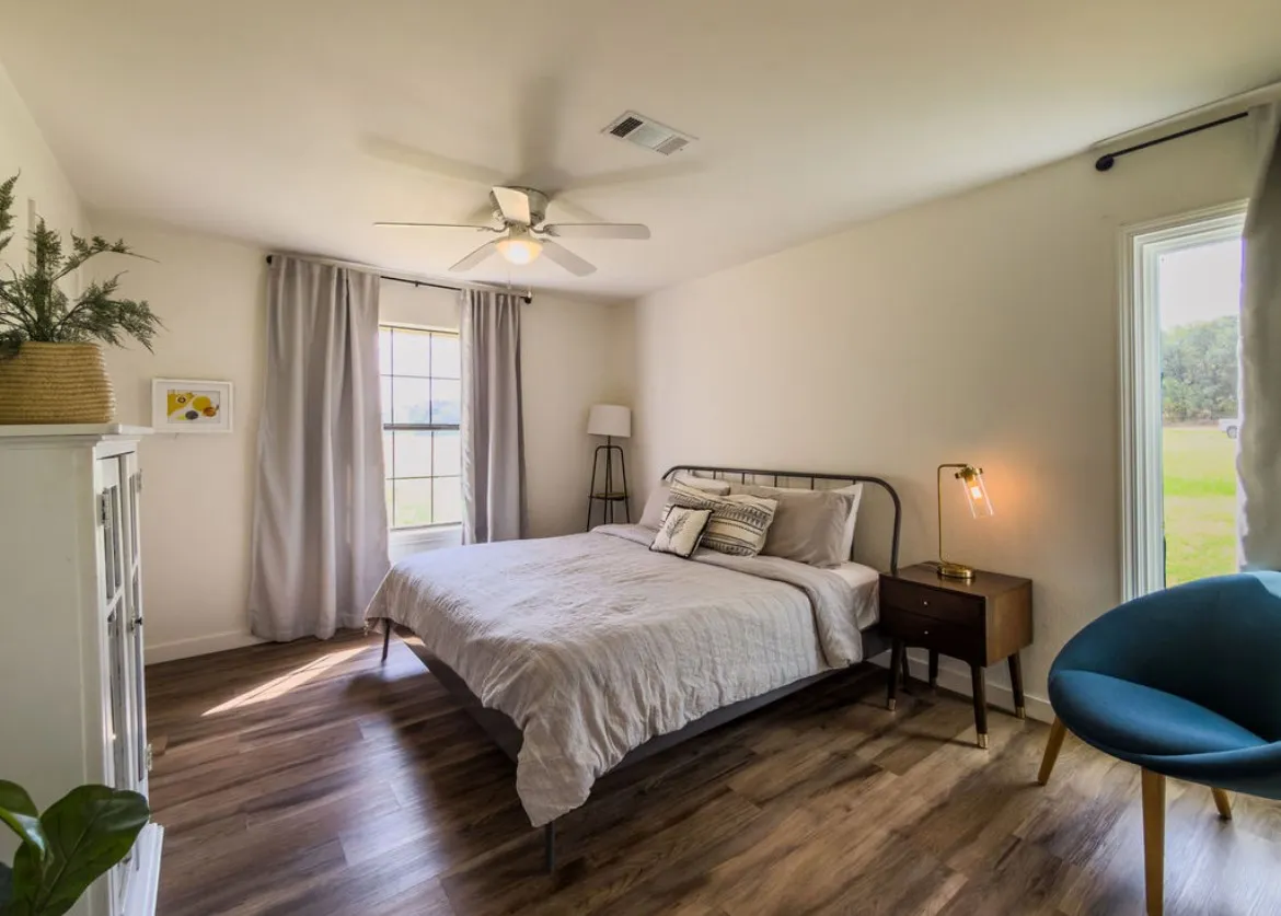 Wood-finish flooring throughout, ceiling fan with integrated lighting, and a large window with natural light